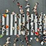 從高空俯瞰都市十字路口，密集的人群正在穿過斑馬線，象徵全球人口紅利的流動與新興市場龐大的潛在消費力。